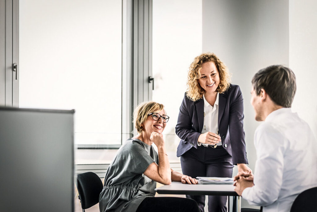 Eine Businessfrau der Munich Re steht in ihrem Office und führt ein Telefonat. Die Aufnahme zeigt eine authentische Arbeitsumgebung und eignet sich für Businessfotografie, die Professionalität und Dynamik vermittelt.