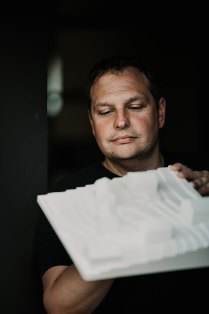 Portrait eines Architekten, der ein Architekturmodell in den Händen hält, professionell und fokussiert