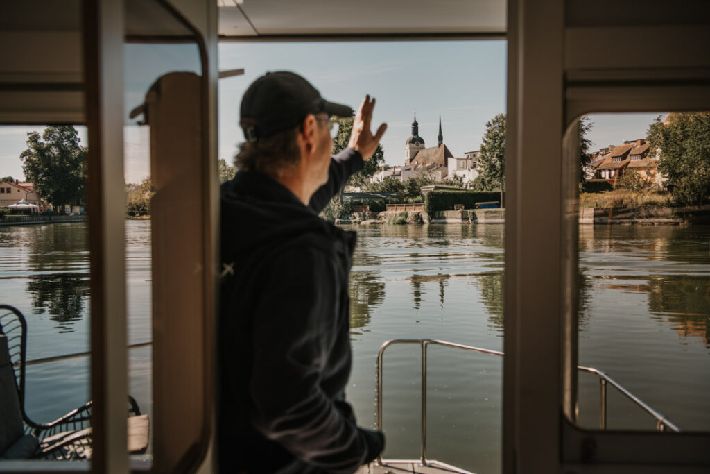 CEO Rolf Hanisch grüßt aus dem fahrenden Rollyboat-Hausboot, Unternehmensfotografie
