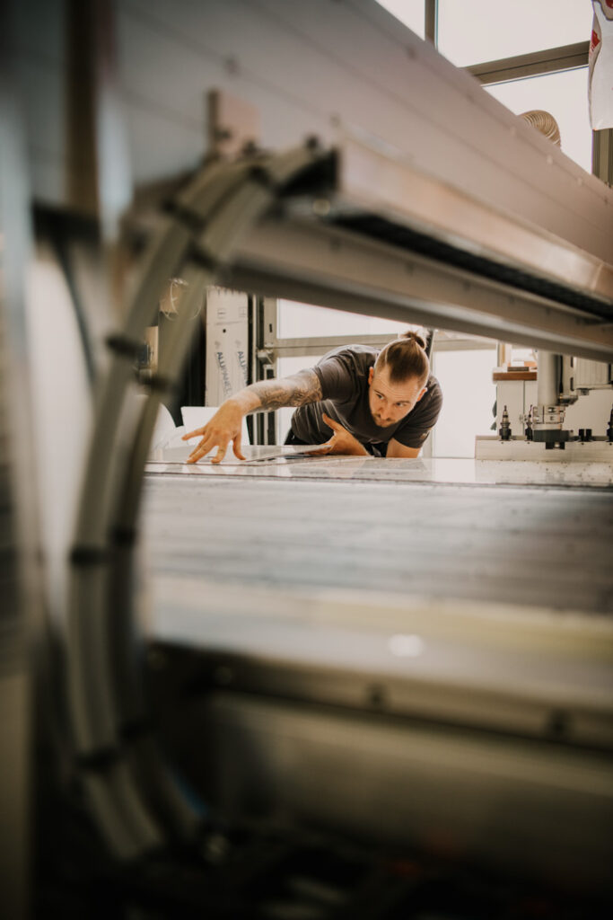 Mitarbeiter von Rollyboat arbeitet an CNC-Fräse für Aludibond-Bauteile in der Werkstatt, Unternehmensfotografie