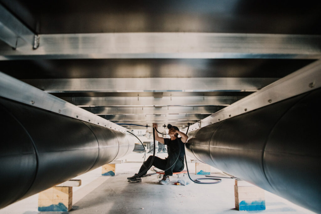 Mitarbeiter von Rollyboat verlegt einen Kabelstrang unter dem Rumpf eines Hausboots, Unternehmensfotografie