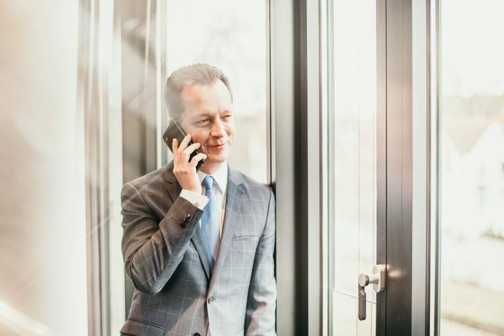 Manager der Santander Bank steht am Fenster und telefoniert – Businessportrait von Businessfotografin Berlin