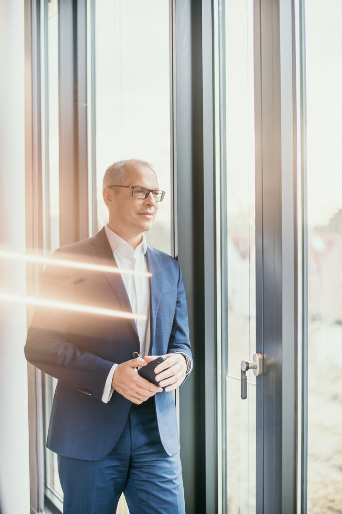 Manager der Santander Bank im blauen Anzug schaut aus dem Fenster – Businessportrait von Businessfotograf Berlin