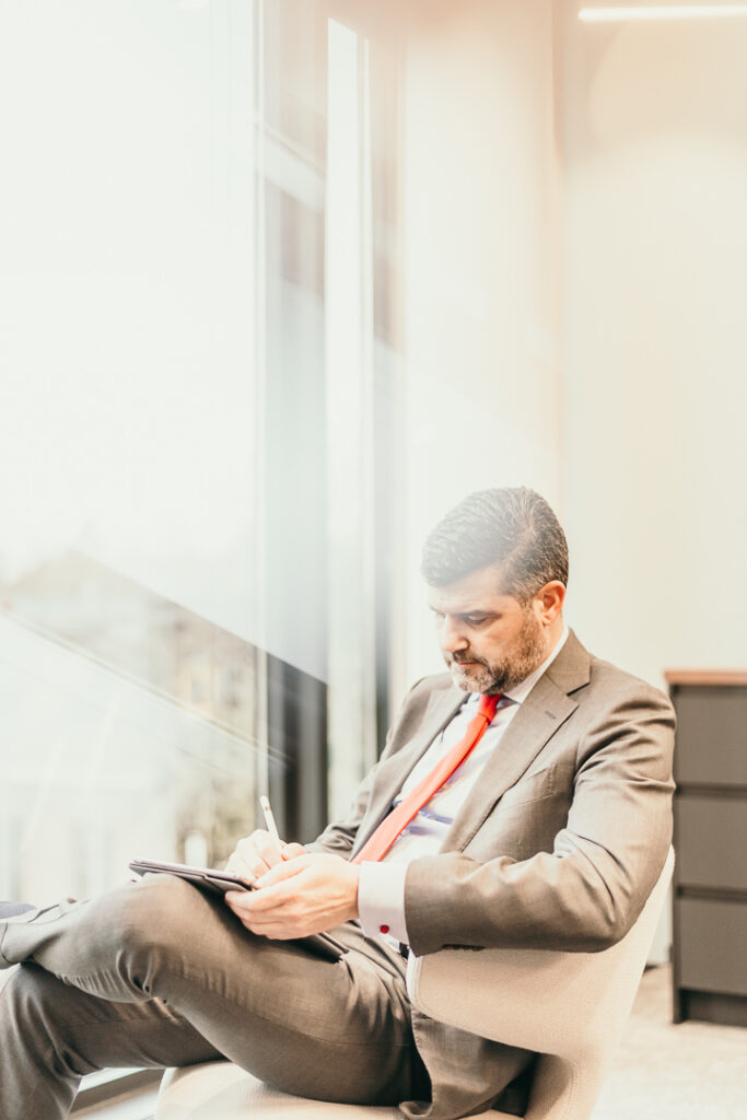 Manager der Santander Bank sitzt am Schreibtisch und macht sich Notizen – Businessfotograf Berlin für Businessfotografie