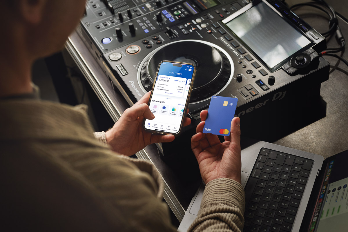 Hände eines DJs beim Onlinebanking mit der Bank Tide auf Tablet und Smartphone - Businessfotograf dokumentiert moderne Werbekampagne