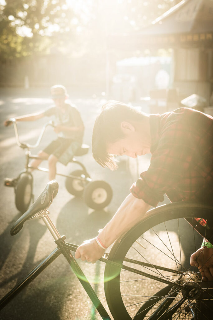 Fahrradmechaniker und Dreiradfahrer arbeiten gemeinsam an einem Fahrrad in einem hippen Fahrradladen in Portland, Oregon, im Sonnenuntergang – businessfotograf.
