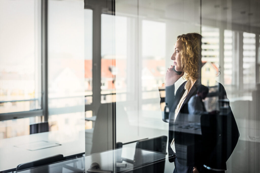 Eine Businessfrau im eleganten Anzug telefoniert konzentriert in ihrem Office, fotografiert mit starker Vordergrundunschärfe – atmosphärische Businessfotografie Hamburg für die MEAG AG.