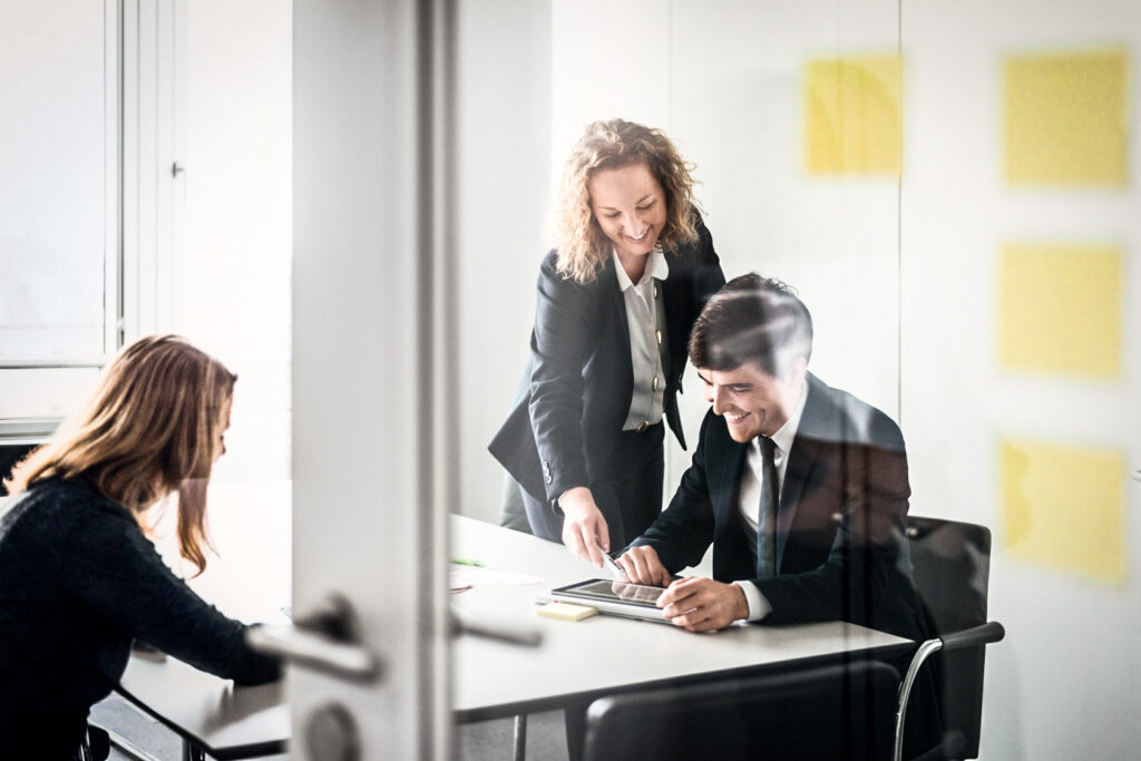 Drei Teilnehmende sitzen an einem Bürotisch und diskutieren konzentriert in ruhiger, atmosphärischer Stimmung – authentisches Businessfoto aus einem Meeting für die MEAG AG.