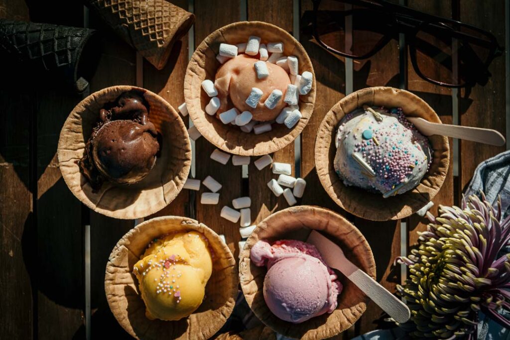 Fünf verschieden angerichtete Eisbecher der Eismanufaktur auf einem Tisch, Draufsicht, Foodfotografie