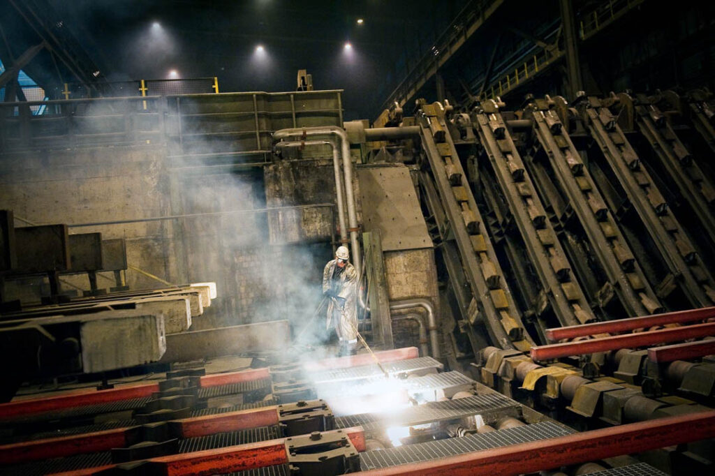 Mitarbeiter der Salzgitter AG in Peine schweißt frisch gepressten Stahlträger, Businessfotografie.