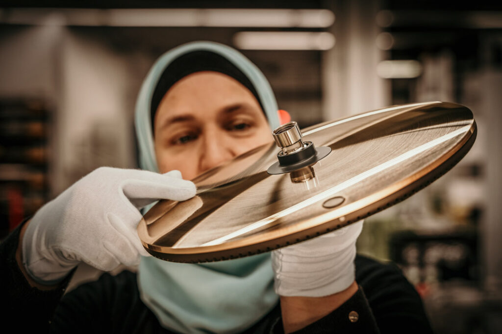 Muslimische Frau mit Kopftuch wirft prüfenden Blick auf Hansgrohe Raindance Alive Premium-Dusche in der Fertigung, corporatefotografie von Businessfotograf