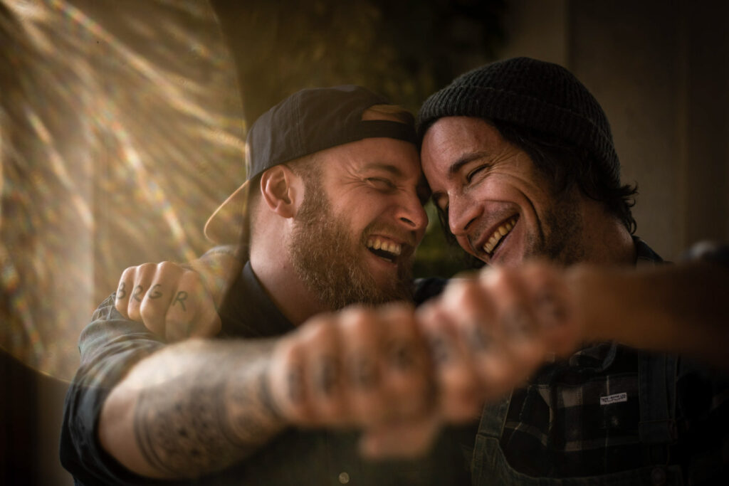 Food Fotografie zeigt Freunde, die sich beim Kochen einen Fist Bump geben und dabei lachen – Foodfotograf fängt die fröhliche Stimmung ein, Food Fotograf inszeniert das gemeinsame Kocherlebnis, Foodfotograf Hamburg und Foodfotograf Berlin dokumentieren die authentische Szene.