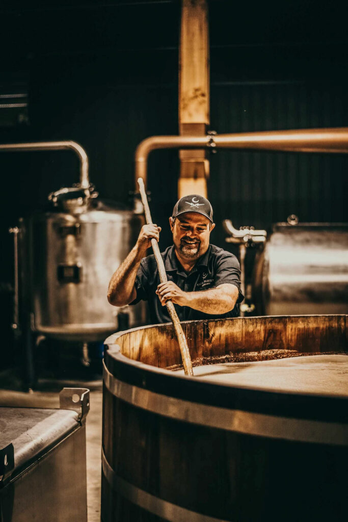Foodfotograf Berlin zeigt Brian Call in der Call Family Distillery in Wilkesboro, North Carolina, USA, wie er seine Maische rührt – handwerkliche Moonshine-Produktion mit Familientradition.