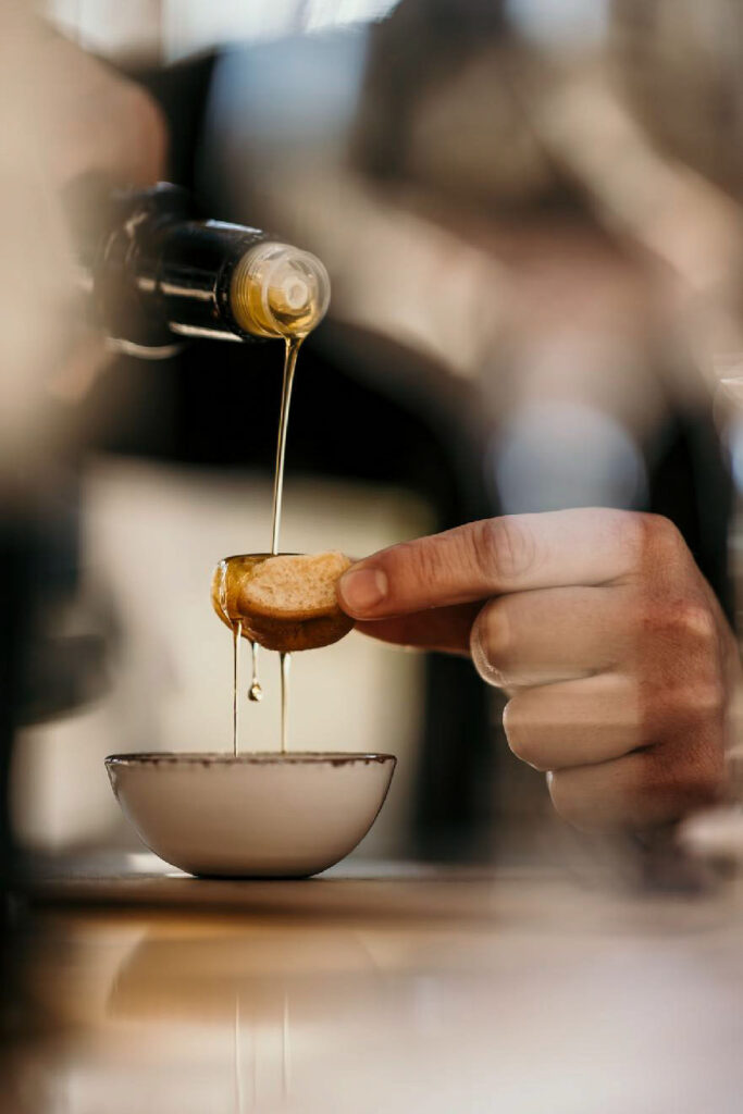 Foodfotograf Hamburg zeigt, wie Olivenöl über Brot gegossen wird – Detailaufnahme für den Geschmackstest.