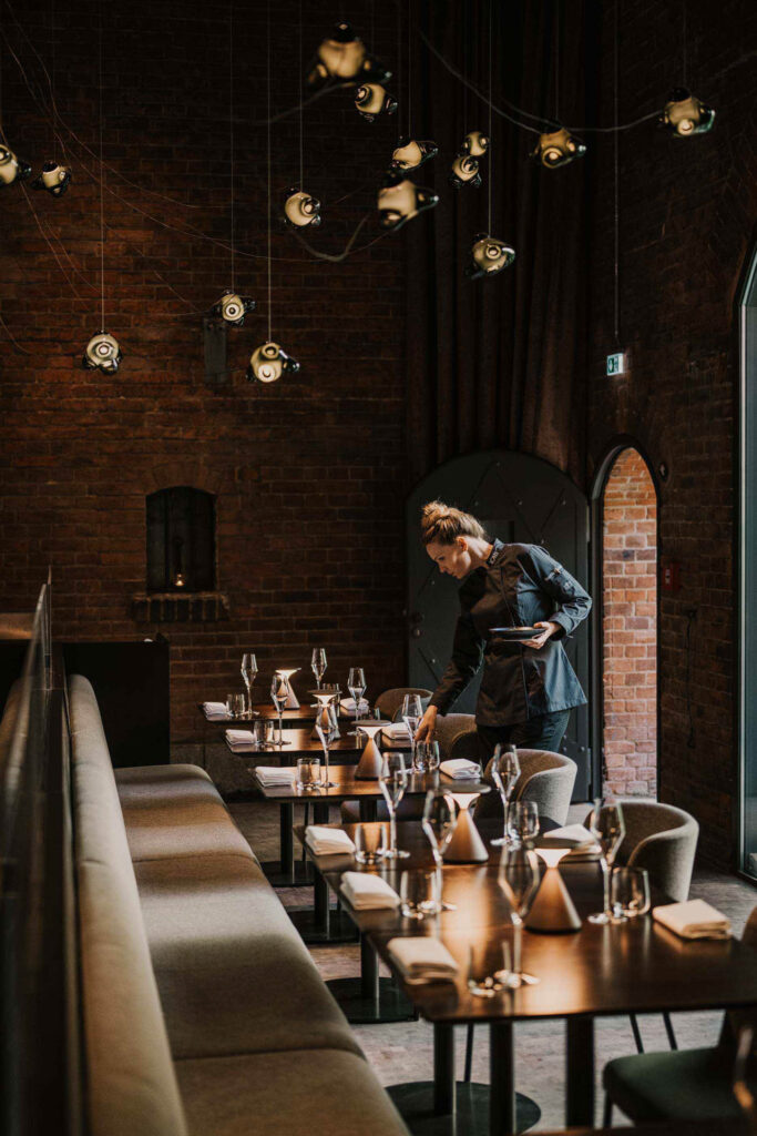 Food photography zeigt Starköchin Sophia Rudolph, wie sie einen Tisch in ihrem Restaurant Lovis im Hotel Wilmina in Berlin eindeckt.