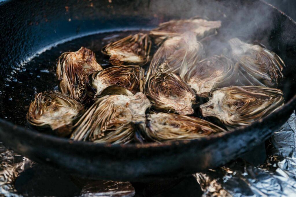 Foodfotograf zeigt die traditionelle Zubereitung von Artischocken in der Pfanne an einem Streetfood-Stand in Catania – authentische italienische Food-Szene im Detail.