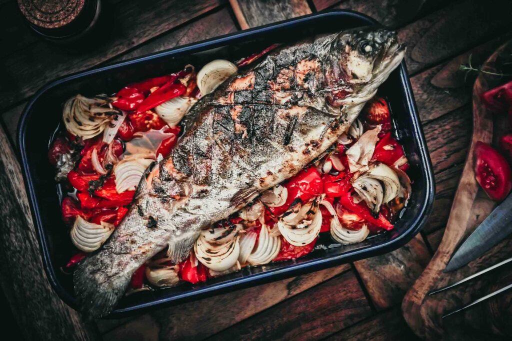 Foodfotograf zeigt eine Makrele auf Gemüse im Bräter – frisch zubereitetes Gericht im Detail.