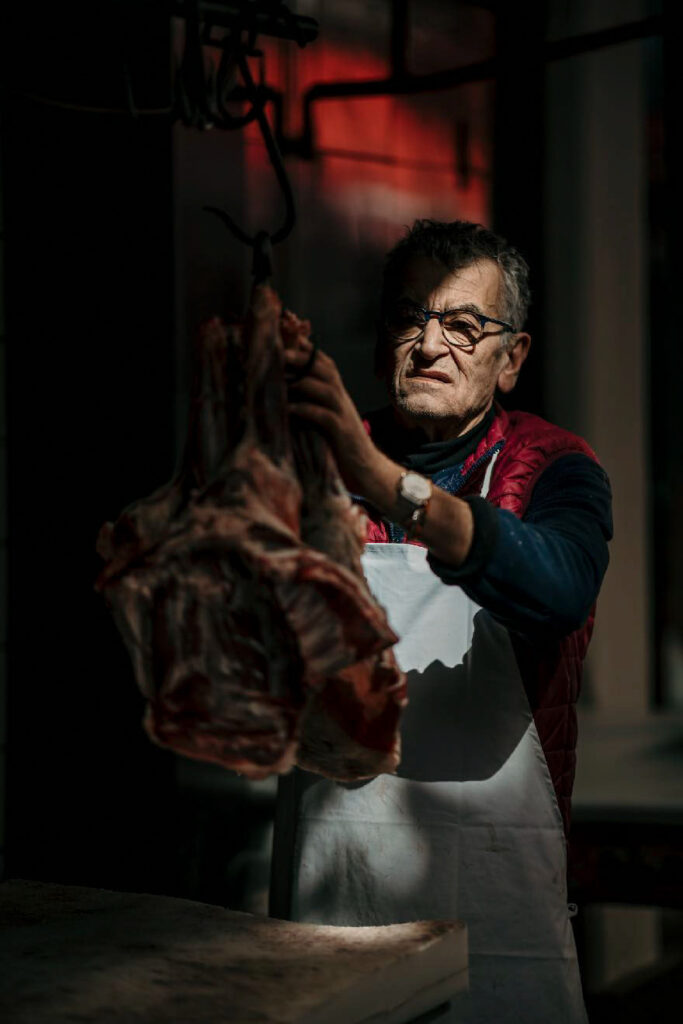 Food Fotograf Berlin zeigt einen Koch auf dem Markt von Catania, der frischen Schinken schneidet – authentische Streetfood- und Marktszene aus Sizilien.