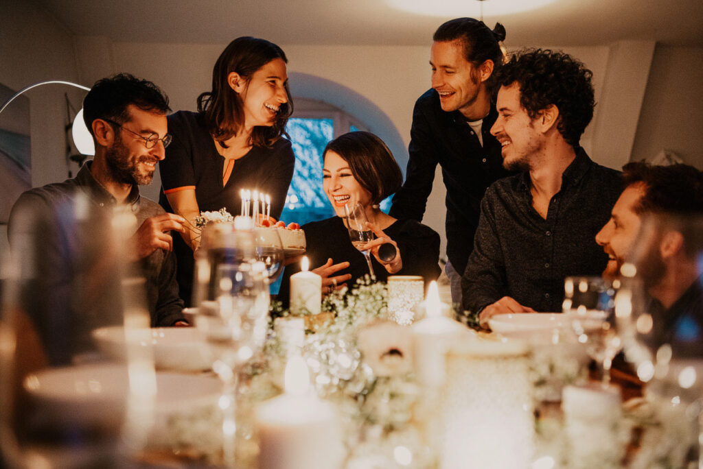 Food Fotografie zeigt eine Geburtstagsparty am Esstisch – Freunde feiern gemeinsam mit einer Torte.