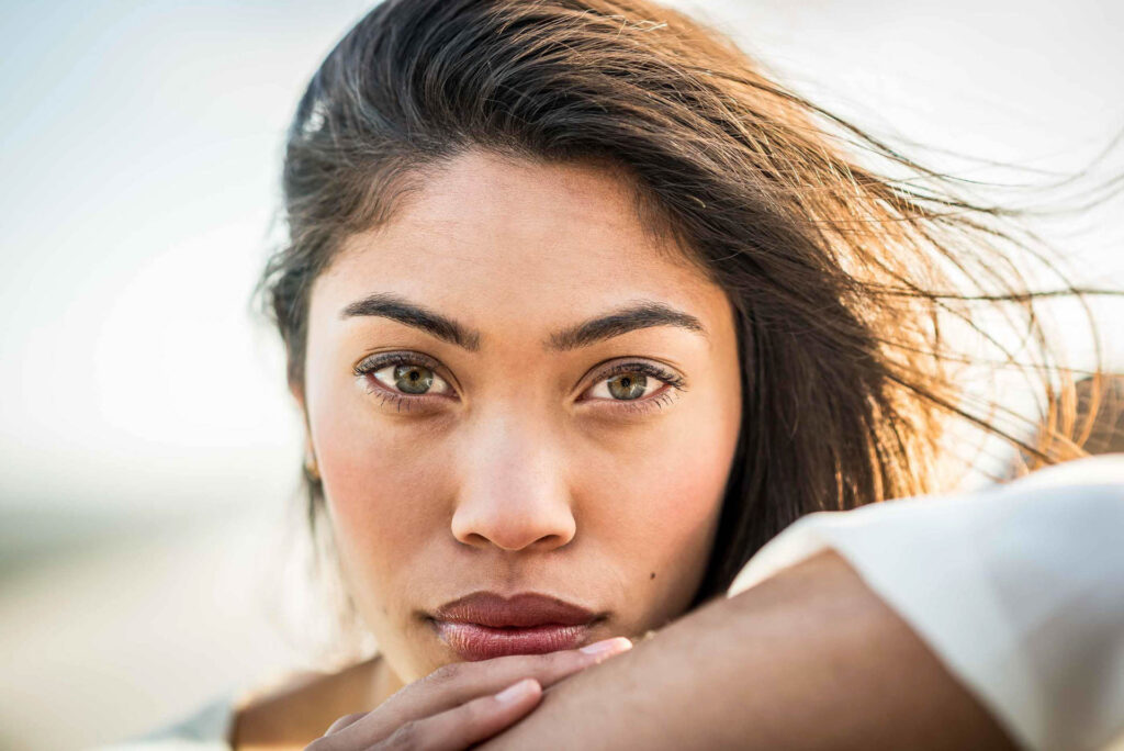 Nahaufnahme einer Frau mit langen, dunklen Haaren und grünen Augen, die in die Kamera schaut.