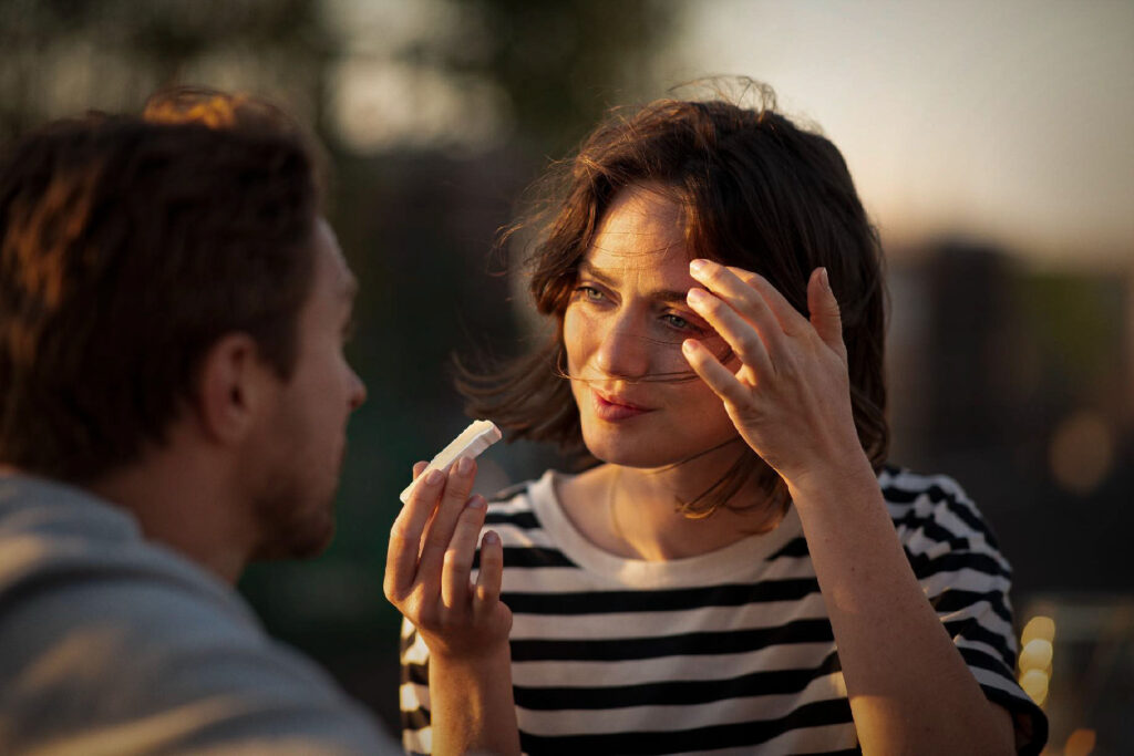 Paar schaut sich genussvoll an, Frau hält ein Stück Geramont Käse in der Hand – fotografiert vom Werbefotograf Berlin.