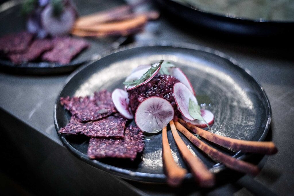 Ein Teller mit Rote-Bete-Crackern, Radieschen und Gemüse-Sticks auf einem dunklen Hintergrund von Foodfotogaf Berlin