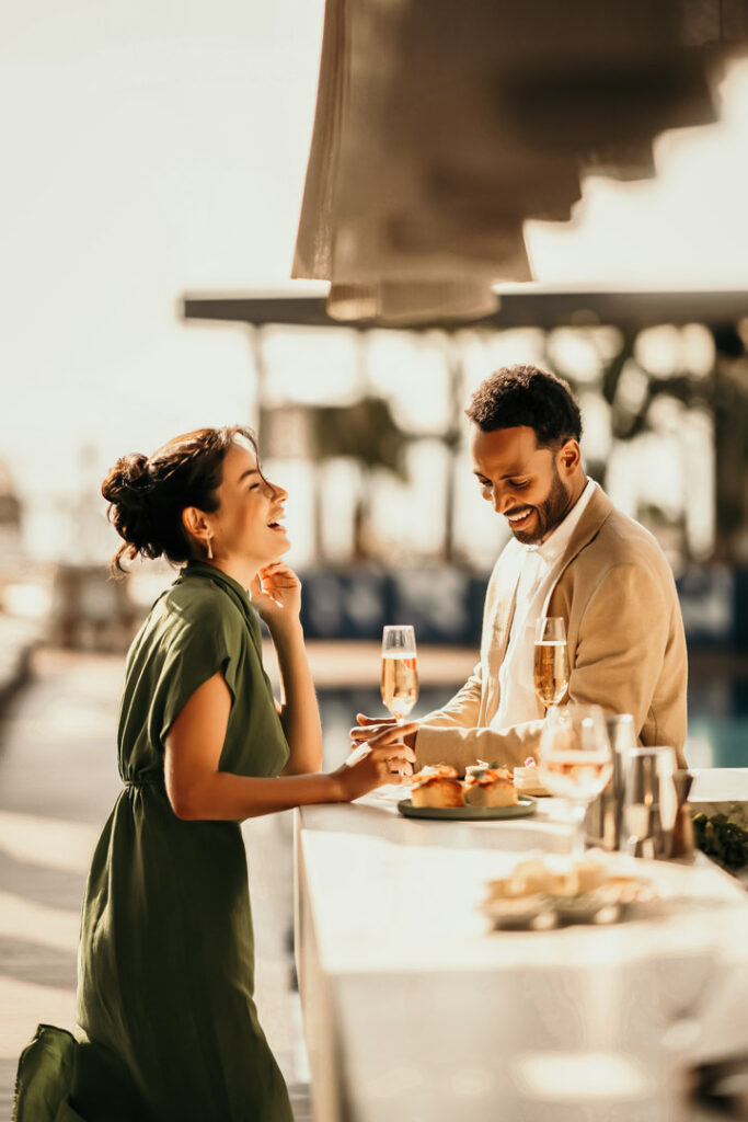 Barmann schenkt einem Paar an der Außenbar im Sofitel ein Getränk ein, vor ihnen Canapés auf dem Tresen – Hotelfoto für Hospitality-Marketing