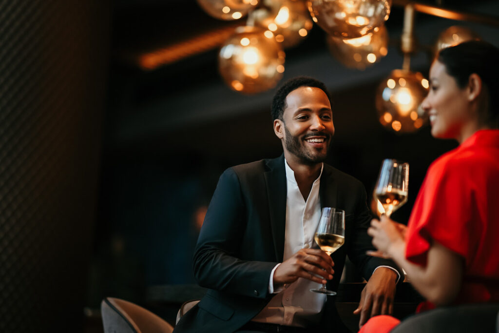 Glückliches Paar chattet lachend an der Sofitel-Hotelbar mit Weingläsern – Werbefotograf für Hospitality-Marketing