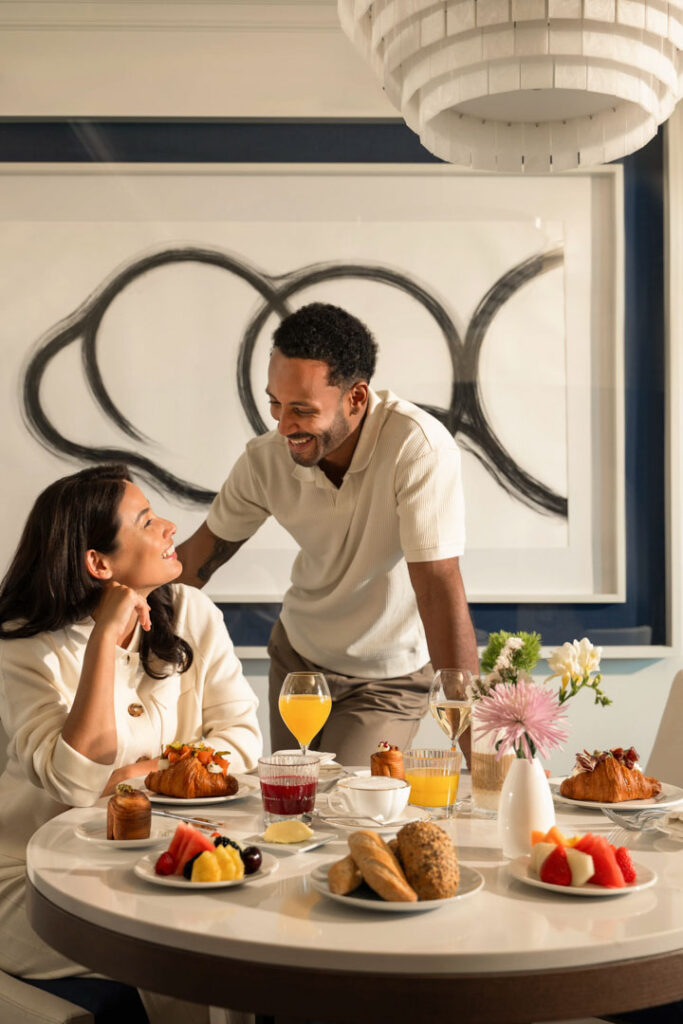 Glückliches Paar genießt Frühstück vom Zimmerservice im Sofitel auf dem Hotelzimmer – Hotelfoto für Hospitality-Marketing