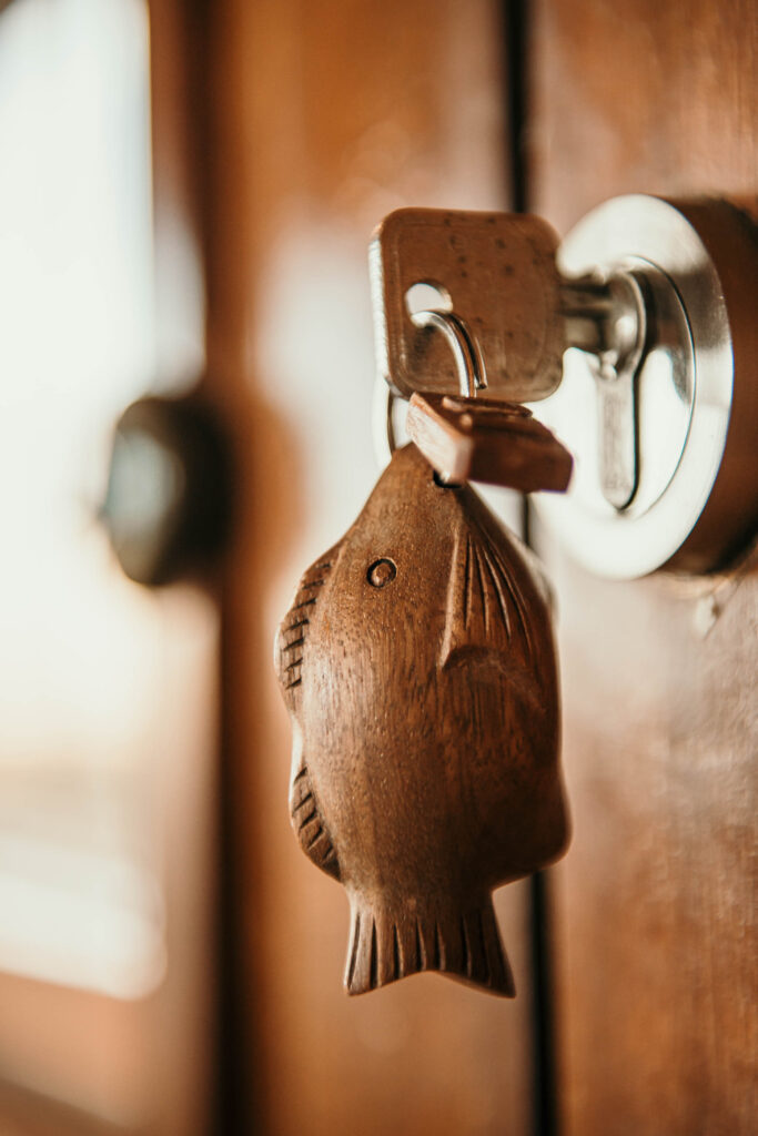 Detail eines geschnitzten Anhängers am Hotelzimmerschlüssel auf dem Kreuzfahrtschiff Amanikan von Aman Hotels – Hotelfotografie.