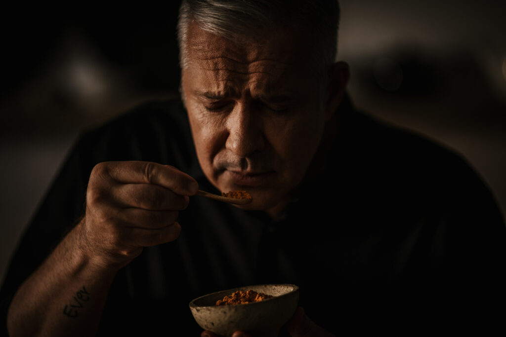 Alexander Herrmann riecht an Gewürz aus einer Gewürzschale, Close-up-Portrait in hochwertiger Foodfotografie von einem Werbefotograf Berlin.