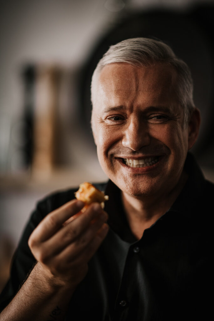 Alexander Herrmann probiert lächelnd ein Gericht, ausdrucksstarkes Portrait in hochwertiger Foodfotografie von einem erfahrenen Werbe-Fotograf.