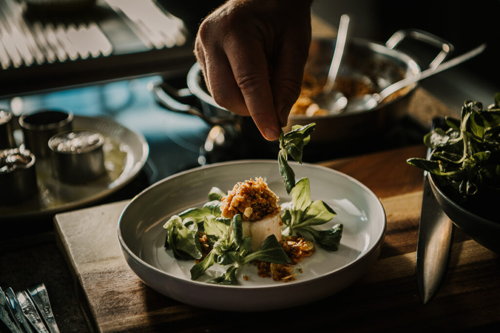 Food-Close-up: Alexander Herrmann richtet einen Fischteller an, stimmungsvolle Foodfotografie aufgenommen von einem erfahrenen Werbefotografin.