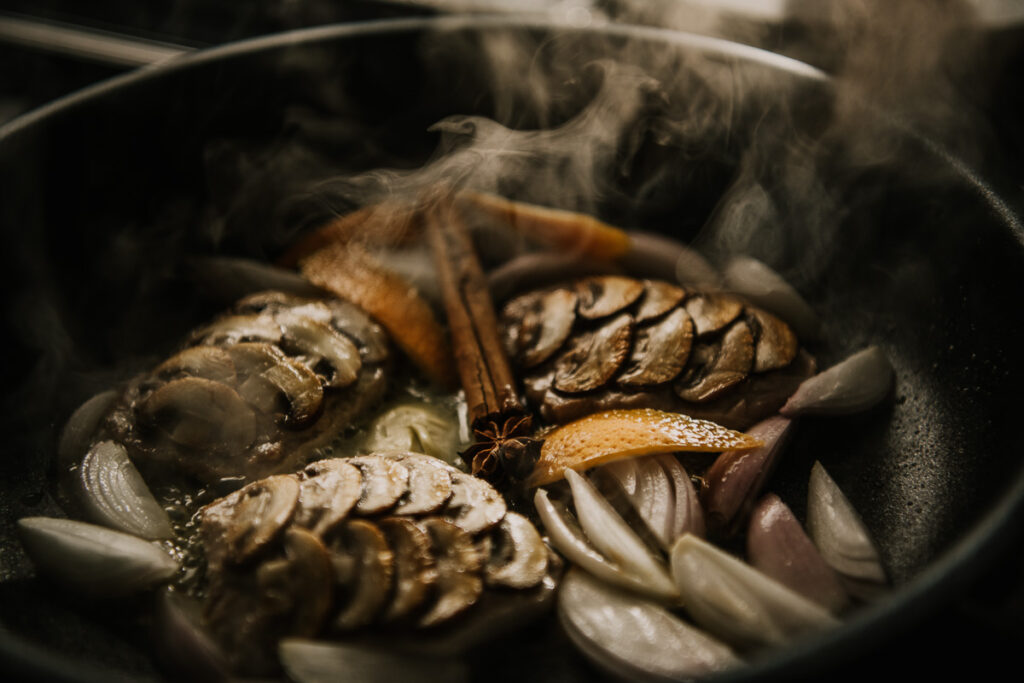 Schweine-Medaillons rösten in Fissler-Pfanne mit Champignons, Zimt, Orangen und Zwiebeln, detailreiches Food-Close-up bei der Zubereitung von einem erfahrenen Foodfotograf Berlin.