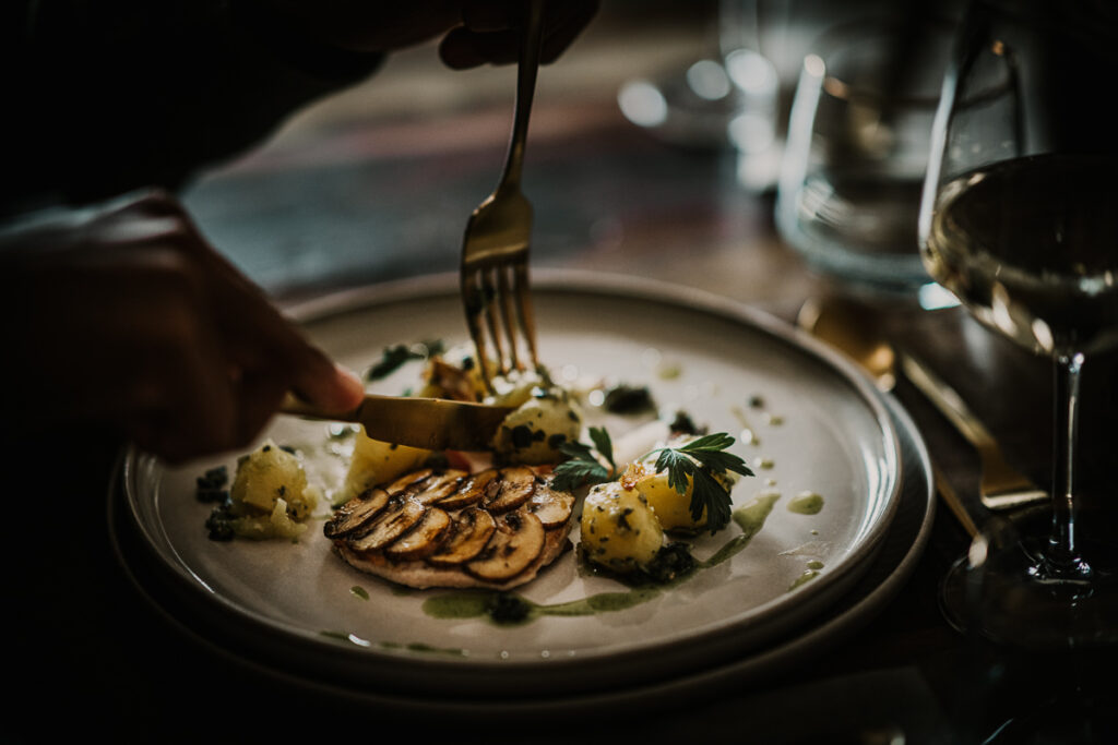 Schweine-Medaillons mit Kartoffeln werden auf einem Teller gegessen, stimmungsvolles Food-Close-up fotografiert von einem erfahrenen Foodfotografen.
