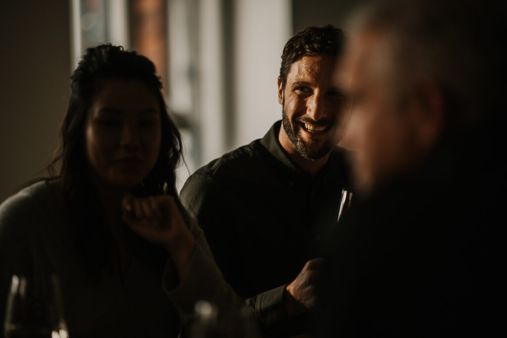 Gäste lachen am Tisch beim Essen, lebendige und authentische Food-Atmosphäre fotografiert von einem spezialisierten Foodfotografen.