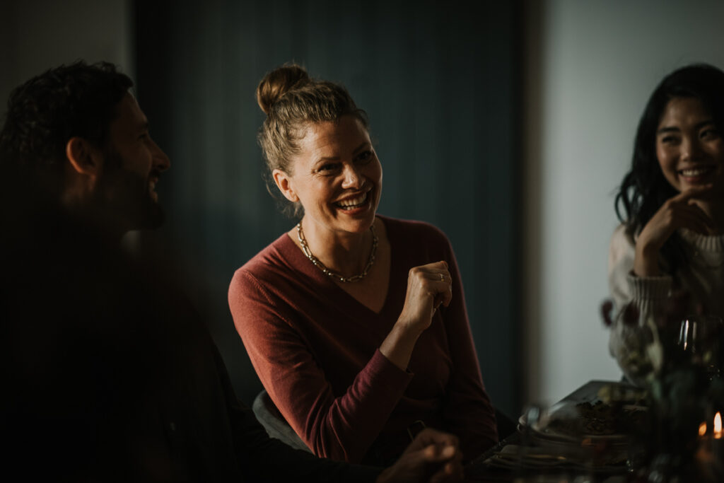 Gäste lachen am Tisch beim Essen, lebendige und authentische Food-Atmosphäre fotografiert von einem spezialisierten Foodfotografen.