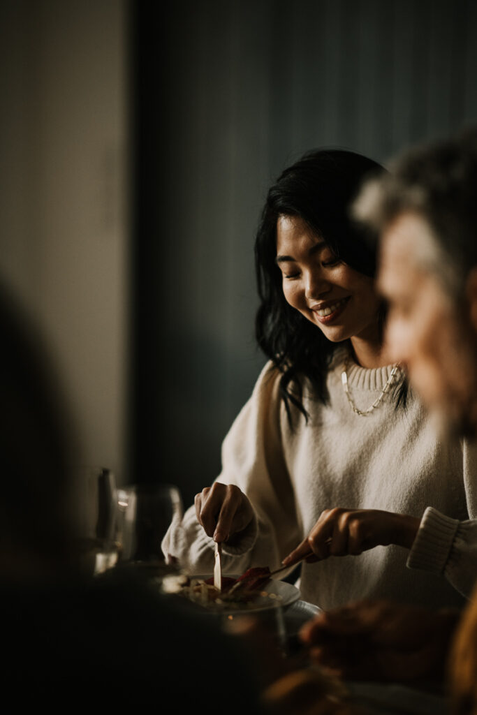 Asiatin genießt Essen von Alexander Herrmann in geselliger Runde, authentischer Genussmoment festgehalten von einem erfahrenen Werbefotografin.