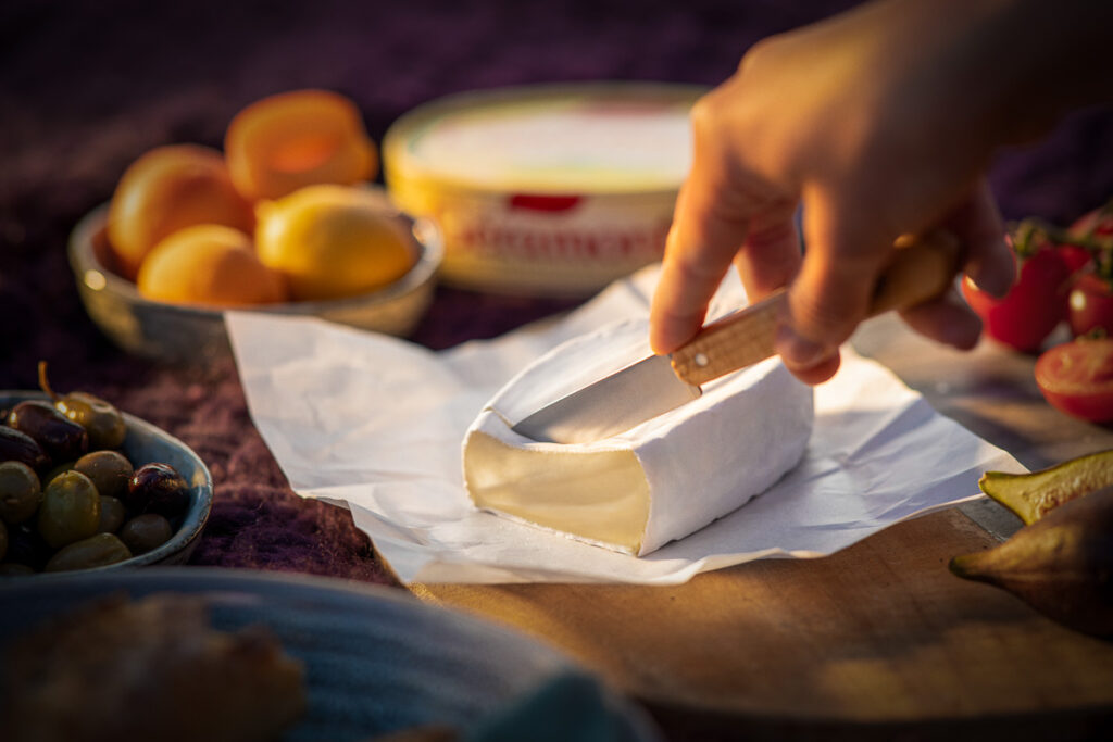 Nahaufnahme von Géramont Käse, der frisch mit Messer portioniert wird, cremige Textur sichtbar. Foodfotografie Werbefoto für Savencia.