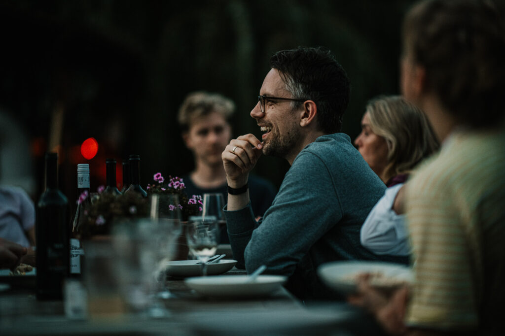 Mann lacht entspannt am Abendessentisch nach einem Business-Meeting – authentische Szene aus einer Businessreportage fotografiert bei einem Networking-Dinner