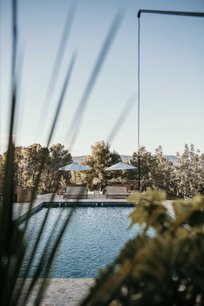 „Hotelpool im Designhotel La Granja Ibiza mit Liegen und Sonnenschirmen – luxuriöse Pool-Atmosphäre in sonnigem Setting, stilvolles Werbefoto.“