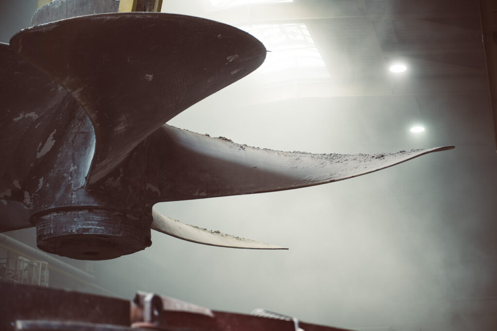 Detailaufnahme einer riesigen Schiffsschraube, die von einem Kran in der Luft gehoben wird, Unternehmensfotografie