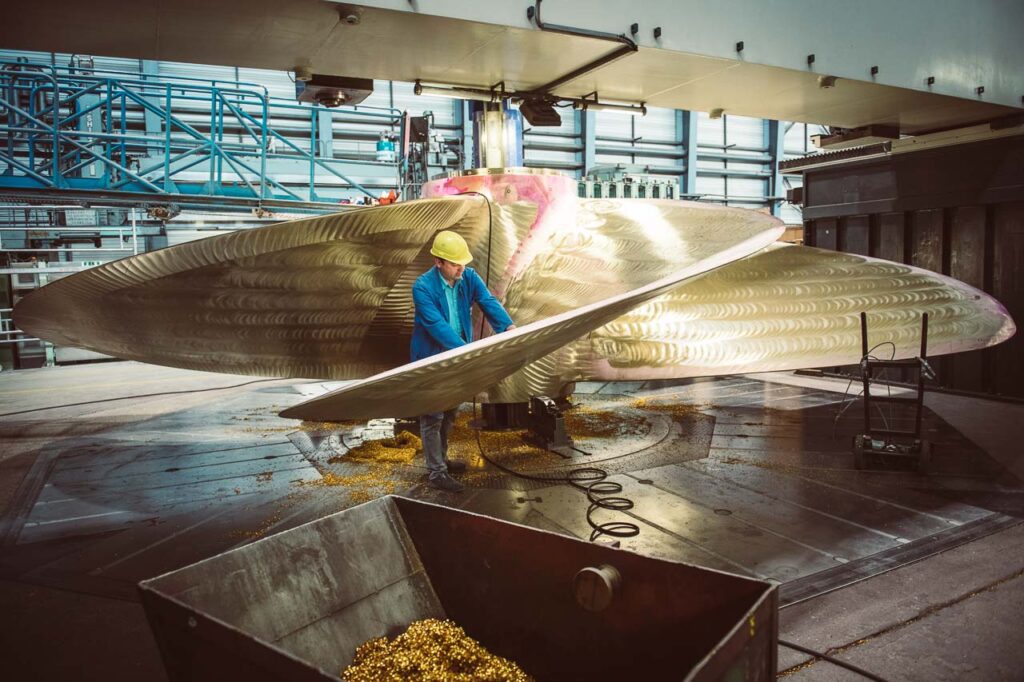 Mitarbeiter der MMG fräst eine Schiffsschraube im Feinschliff per Hand in der Werkshalle, Unternehmensfotografie