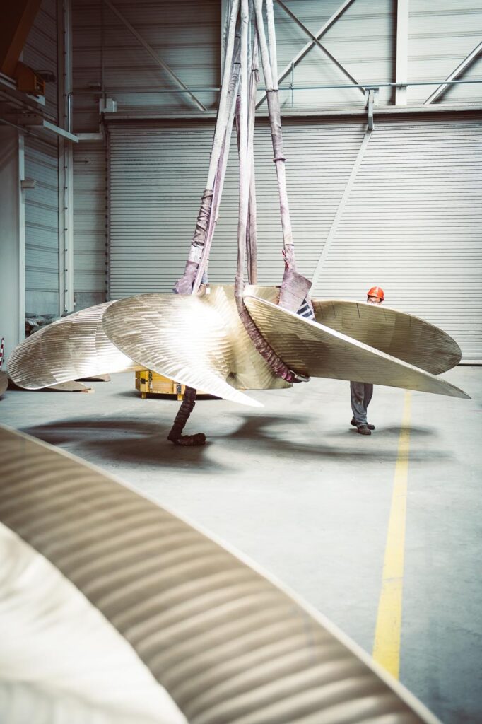 Riesige Schiffsschraube wird in der Werkshalle der MMG verladen, Waren an der Müritz, Mecklenburg-Vorpommern, Unternehmensfotografie, Mitarbeiter drückt Schraube in die richtige Richtung