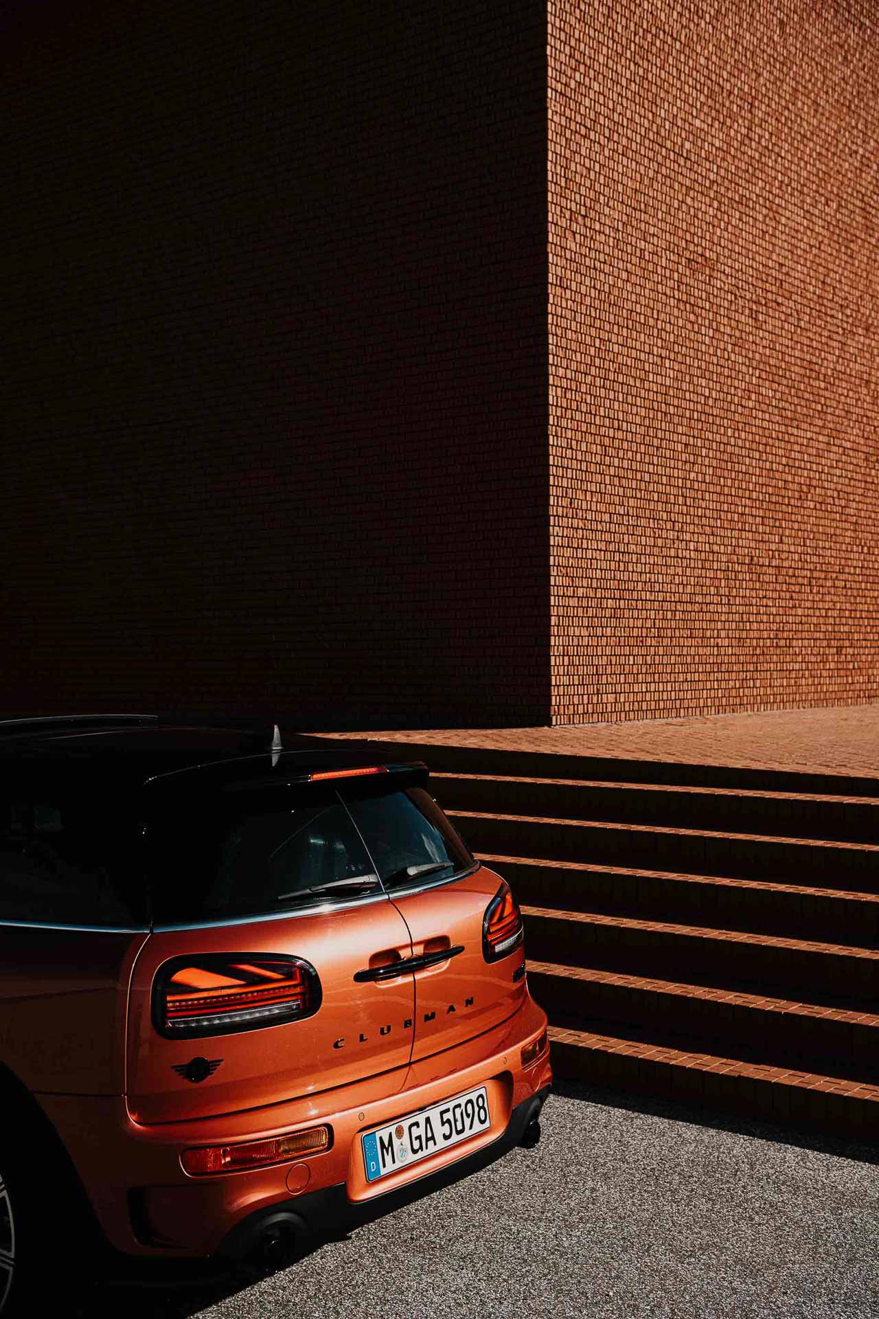 Authentisches Duo-Portrait in natürlicher, stimmungsvoller Umgebung, Malte und Jessika Jäger, Werbefotografen und Videographen Berlin Heck eines roten Mini Clubman vor spektakulärer Architektur von Herzog & de Meuron auf dem Vitra Campus – stilvolles Automotive- und Architektur-Fotografie-Motiv von Werbefotograf in Berlin