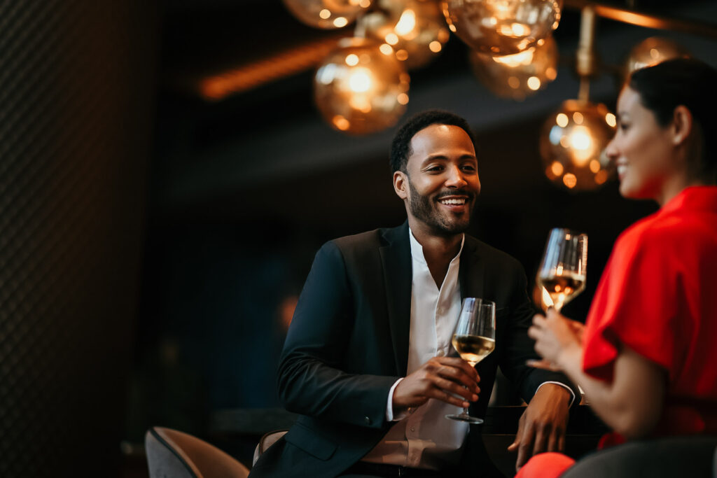 Glückliches Paar chattet lachend an der Sofitel-Hotelbar mit Weingläsern – Werbefotograf für Hospitality-Marketing