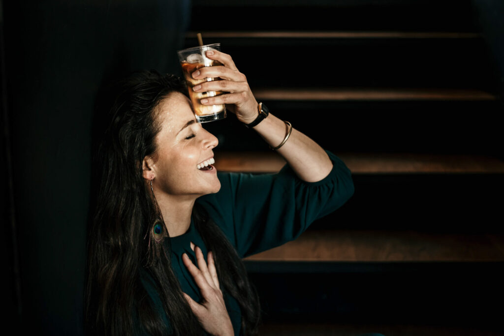 Foodfotograf Berlin zeigt eine schöne Frau, die sich die Stirn mit einem Glas Eiscafé kühlt – erfrischender Genuss an einem warmen Tag.