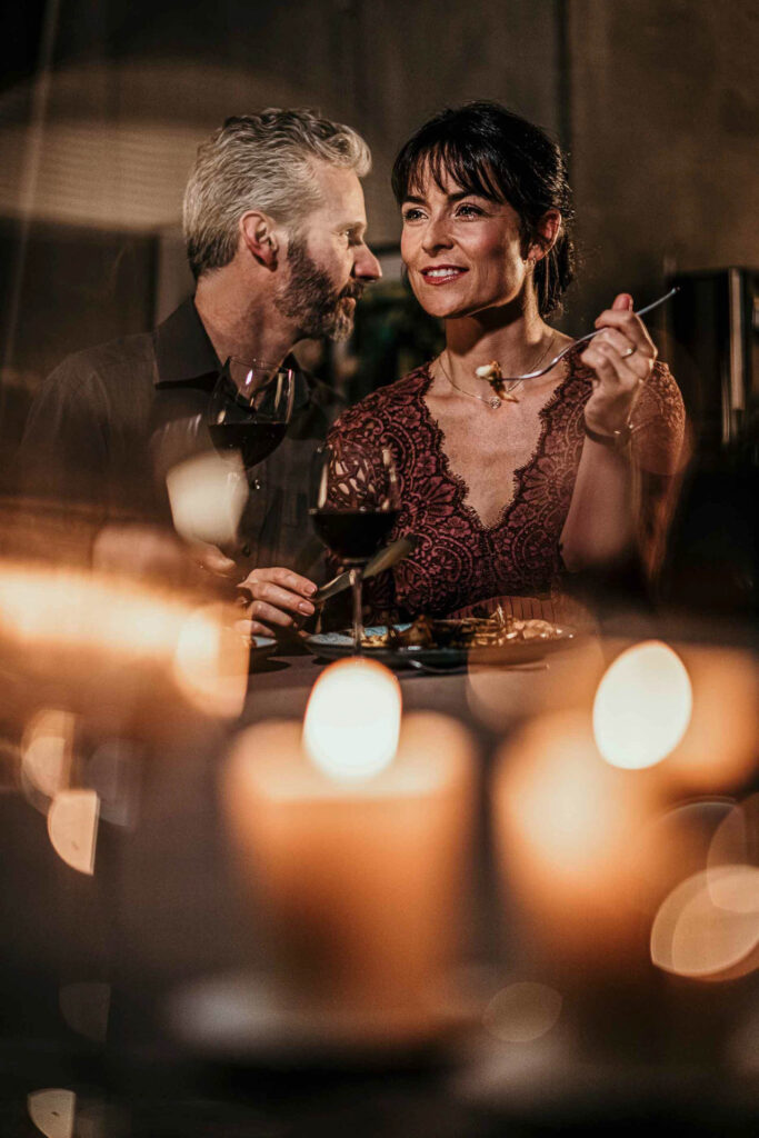Foodfotograf Berlin fängt ein Paar ein, das sich einfühlsam an einem festlich gedeckten Tisch unterhält – stimmungsvolle Atmosphäre, fotografiert für WMF und Ogilvy.