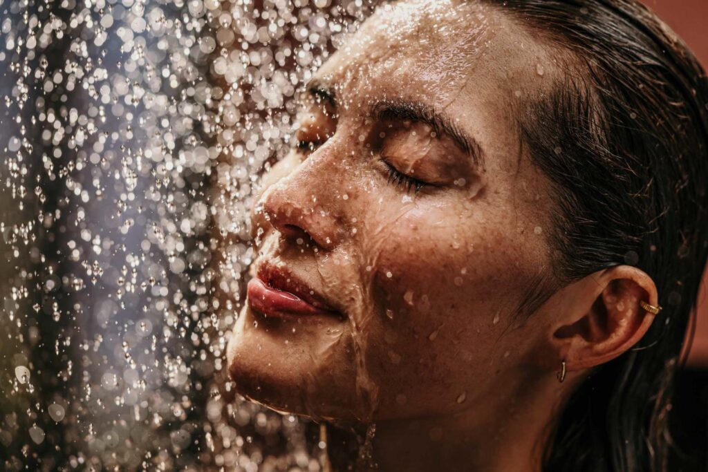 Close-up einer Frau, die unter der Dusche genießt, Wasser läuft über ihr Gesicht – Werbefotografie, Werbefotograf Berlin.