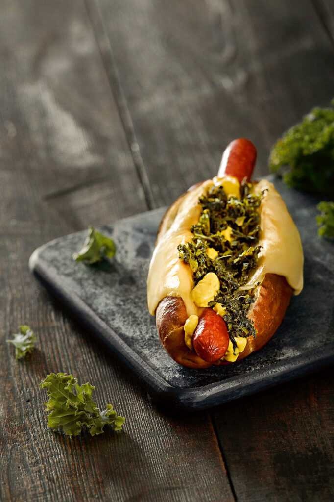 Foodfotograf hält einen Grünkohl-Laugen-Hotdog fest – fotografiert für Werbung von BackWerk.